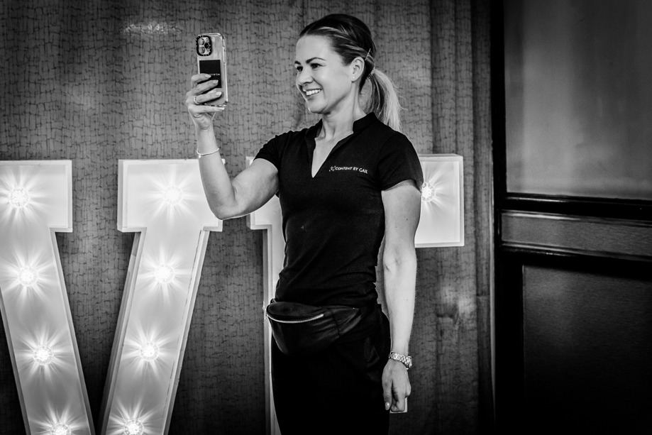 Gail Irvine - owner of Content by Gail, a Scottish wedding content creator - smiles as she snaps a picture at a wedding.